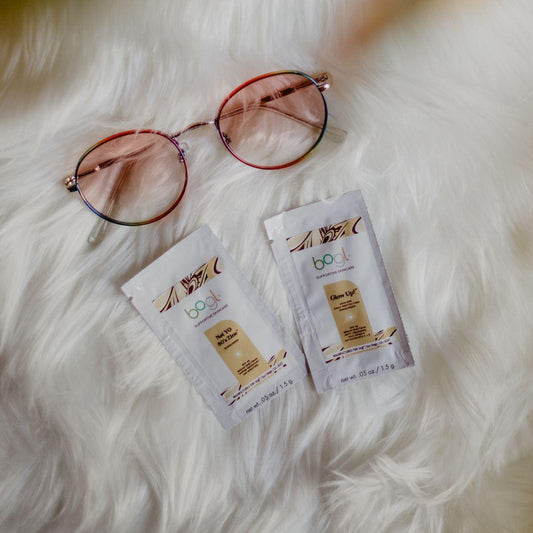 two of bogl's spf sample packets on white fluffy background with sunglasses