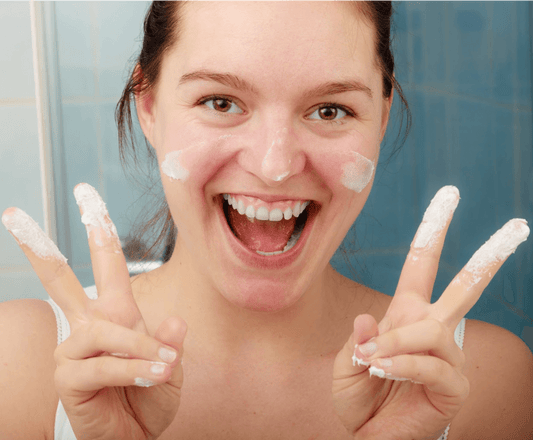 smiling women with moisturizer on fingers giving the peace sign